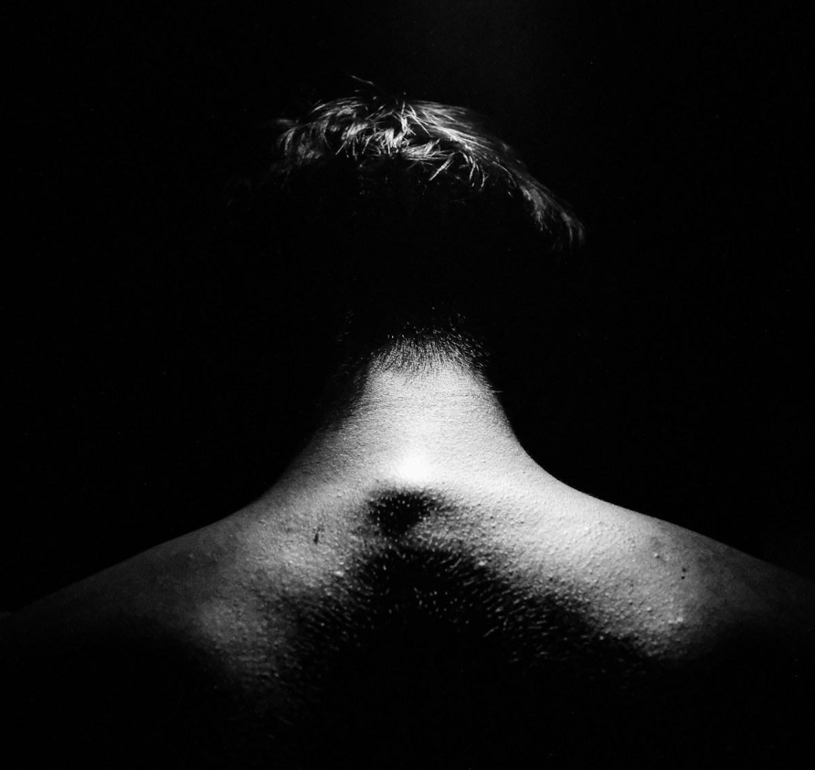 Shirtless man with his head down.